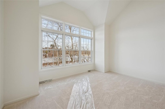 empty room featuring light carpet, plenty of natural light, and vaulted ceiling