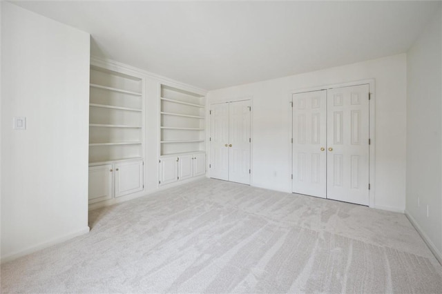 unfurnished bedroom with two closets and light colored carpet