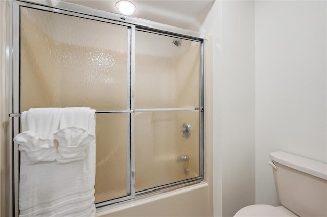 bathroom with toilet and combined bath / shower with glass door