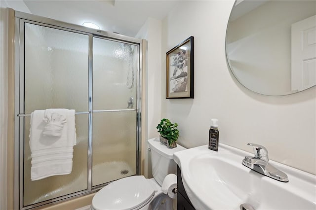 bathroom featuring toilet, a shower with door, and sink