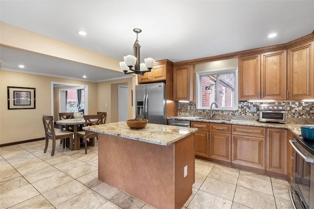 kitchen featuring sink, stainless steel appliances, light stone counters, a kitchen island, and decorative light fixtures