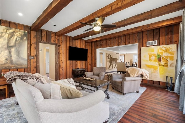 living room featuring ceiling fan, dark hardwood / wood-style flooring, beam ceiling, and wood walls