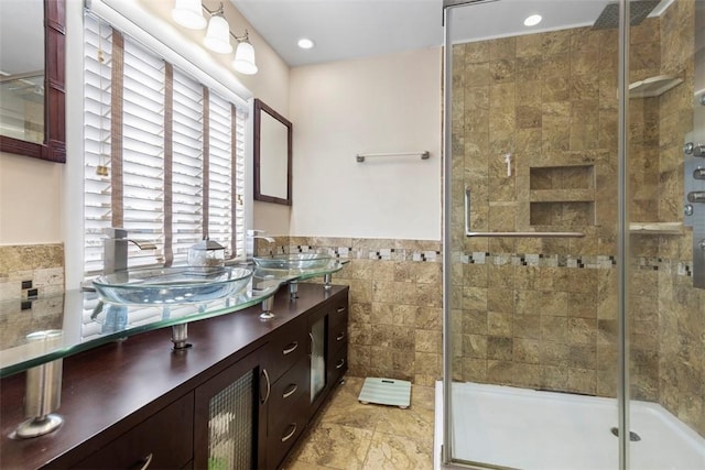 bathroom with a shower with door, vanity, and tile walls