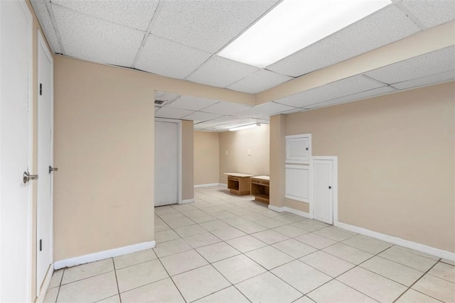 basement with light tile patterned floors and a drop ceiling