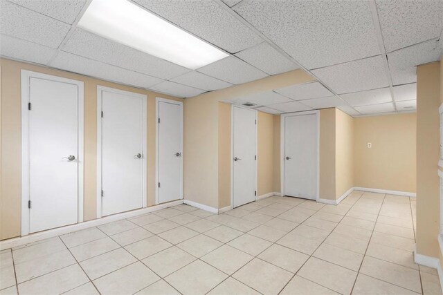 basement with a paneled ceiling and light tile patterned floors