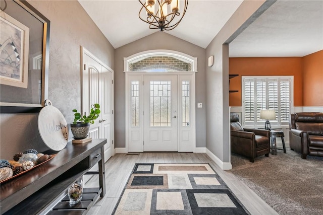 entrance foyer featuring plenty of natural light, vaulted ceiling, light hardwood / wood-style flooring, and a notable chandelier