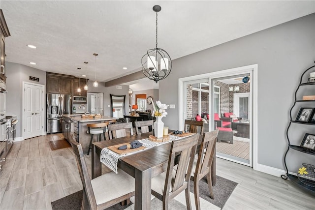 dining room with sink, a notable chandelier, and light hardwood / wood-style floors