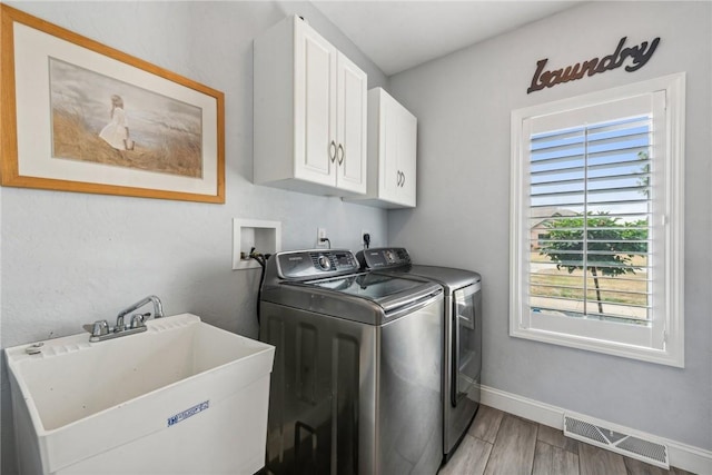 washroom with sink, hardwood / wood-style floors, cabinets, and independent washer and dryer