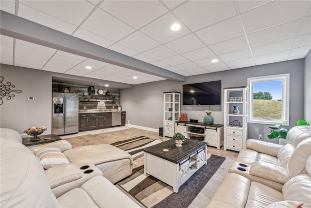 living room featuring a drop ceiling, light hardwood / wood-style floors, and indoor wet bar