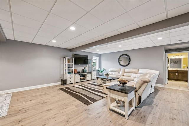 living room with a paneled ceiling and light wood-type flooring