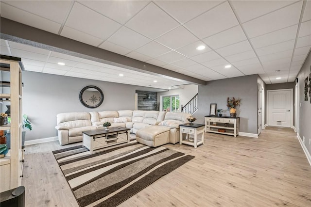 living room featuring light hardwood / wood-style floors and a drop ceiling