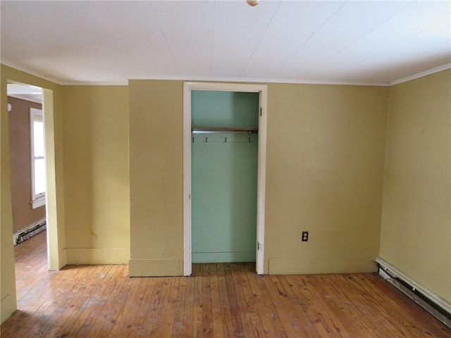 unfurnished bedroom featuring baseboard heating, a closet, and light wood-type flooring