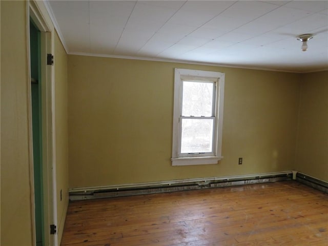 empty room featuring baseboard heating, ornamental molding, and wood-type flooring