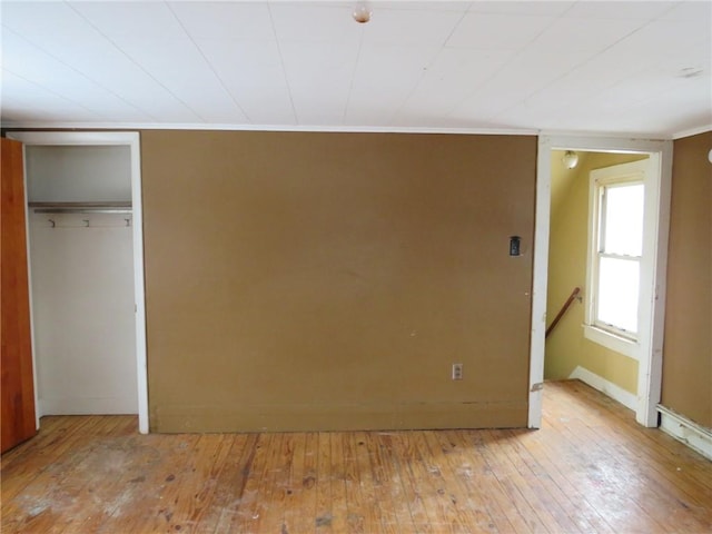 unfurnished bedroom with crown molding, light hardwood / wood-style flooring, and a closet