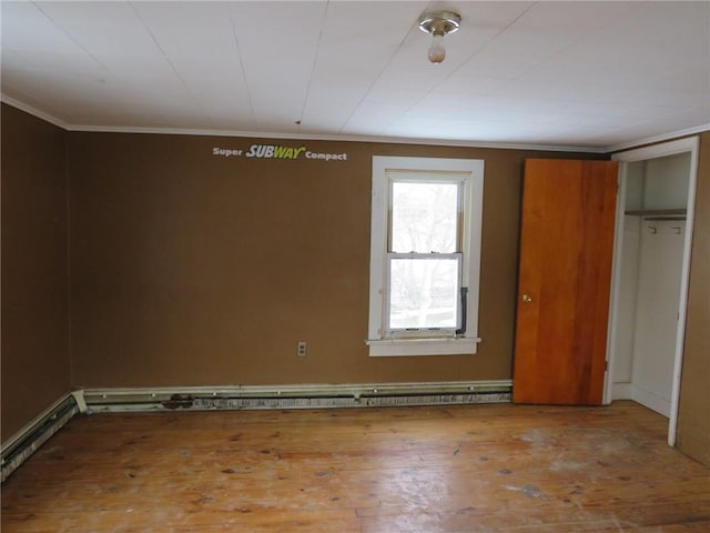 spare room featuring a baseboard heating unit, wood-type flooring, and ornamental molding