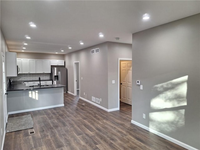 kitchen featuring sink, white cabinetry, tasteful backsplash, dark hardwood / wood-style floors, and stainless steel fridge