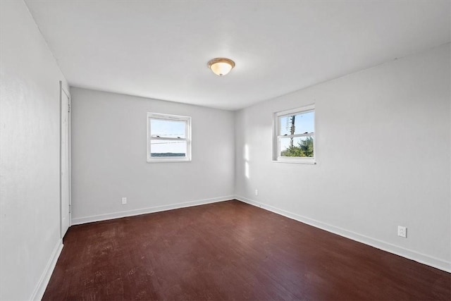 unfurnished room featuring a wealth of natural light and dark hardwood / wood-style floors