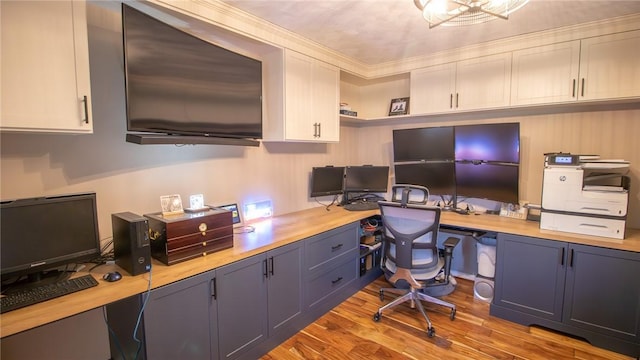 office area featuring crown molding, built in desk, and light wood-type flooring