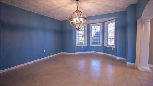 empty room featuring a chandelier and ornate columns