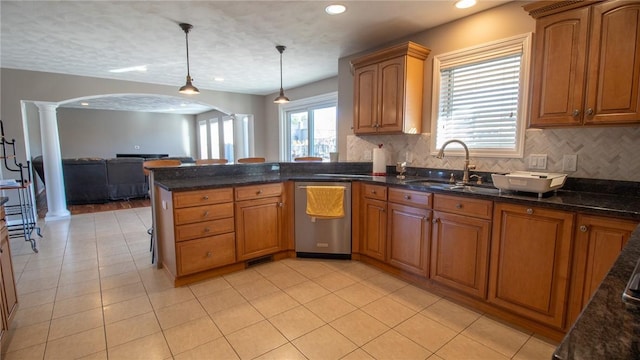 kitchen featuring sink, ornate columns, hanging light fixtures, dishwasher, and backsplash