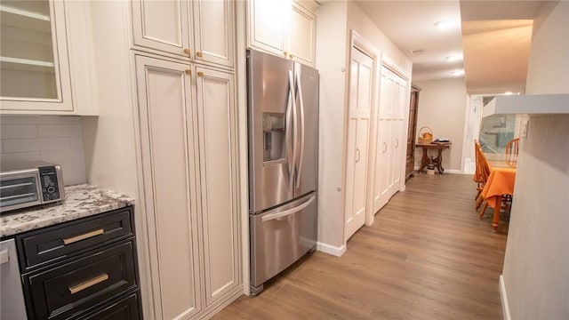 kitchen featuring stainless steel appliances, light stone countertops, light hardwood / wood-style floors, and white cabinets