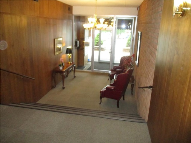 sitting room with an inviting chandelier, carpet floors, and wood walls