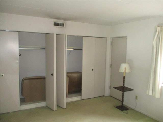 unfurnished bedroom with multiple closets and light colored carpet