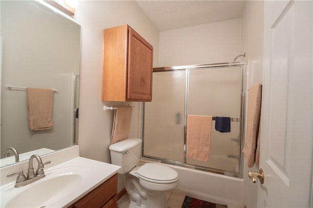 full bathroom with bath / shower combo with glass door, vanity, a textured ceiling, and toilet