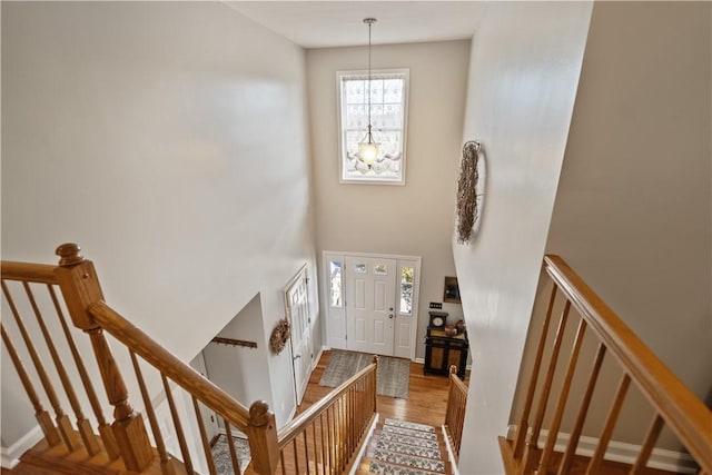 entryway with a towering ceiling, hardwood / wood-style floors, and a chandelier