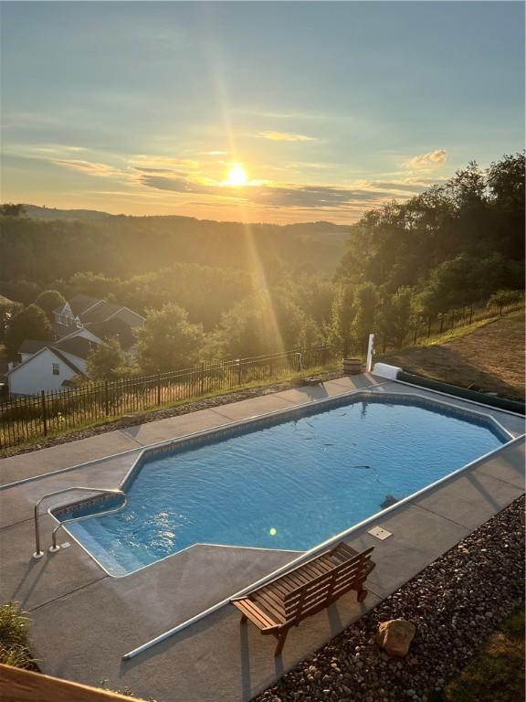 pool at dusk with a patio and a mountain view