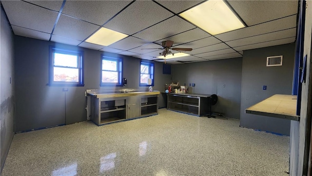 basement featuring a paneled ceiling and ceiling fan