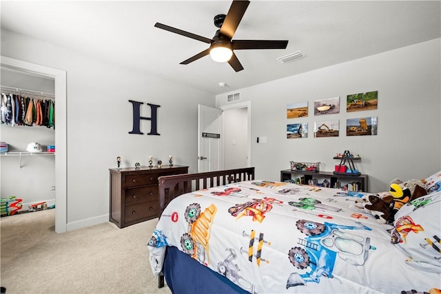 carpeted bedroom featuring ceiling fan, a closet, a walk in closet, and visible vents