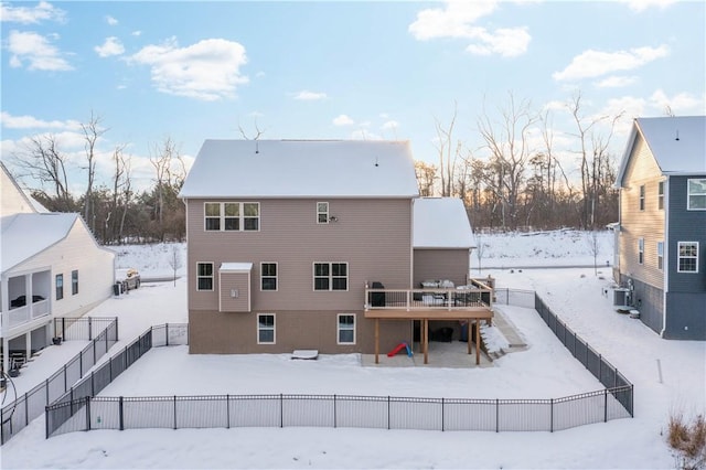 snow covered property with fence, a deck, central AC unit, and stairs