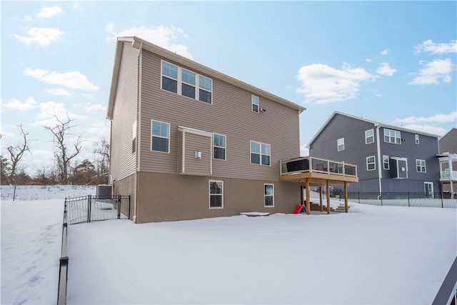 snow covered property with central AC, fence, a gate, and stucco siding