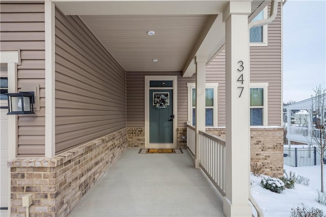 snow covered property entrance with brick siding