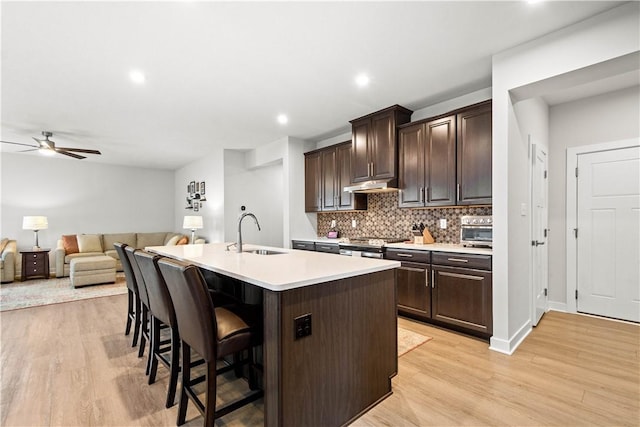 kitchen featuring dark brown cabinets, stove, a kitchen breakfast bar, and a sink