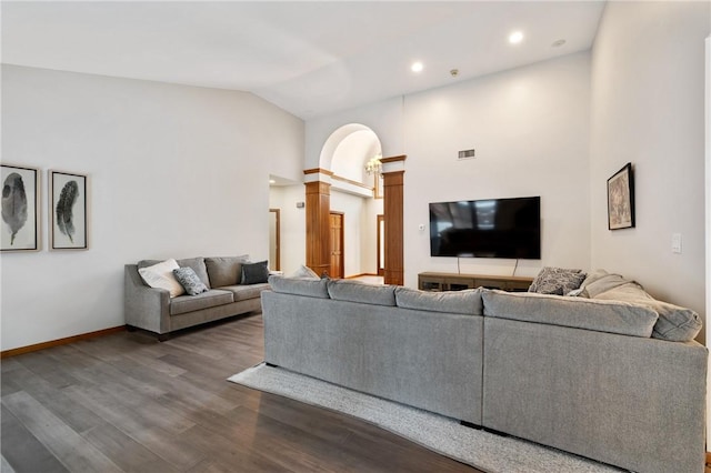 living room featuring decorative columns, wood-type flooring, and high vaulted ceiling