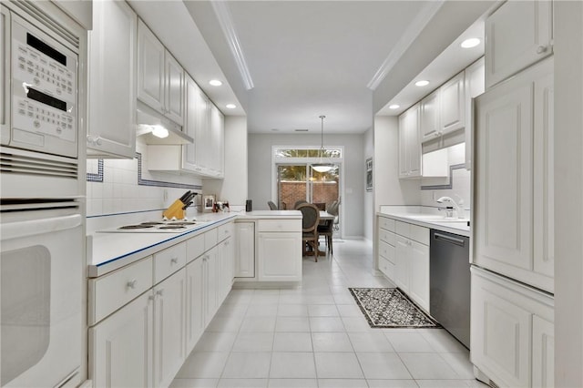 kitchen with tasteful backsplash, hanging light fixtures, kitchen peninsula, white appliances, and white cabinets