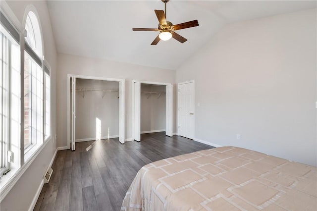 bedroom with ceiling fan, dark wood-type flooring, high vaulted ceiling, and multiple closets