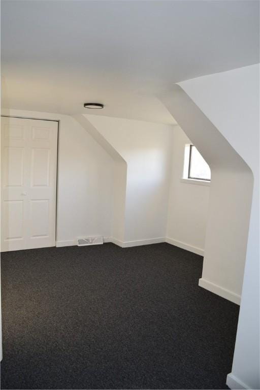 bonus room featuring dark colored carpet and vaulted ceiling