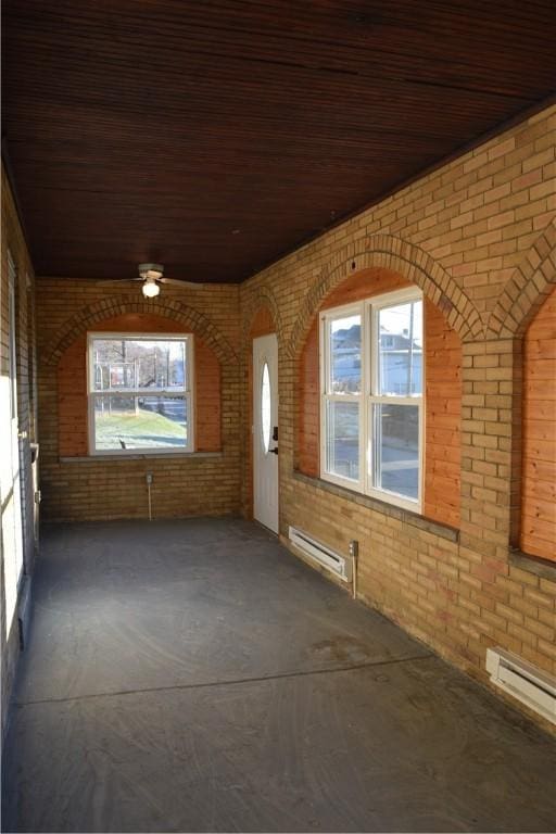 interior space featuring brick wall, a baseboard heating unit, and a wealth of natural light