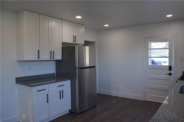 kitchen featuring dark hardwood / wood-style floors, dark stone countertops, stainless steel fridge, and white cabinets