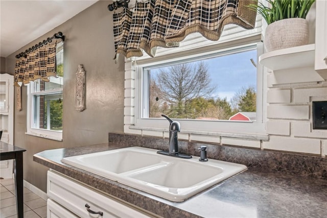 kitchen with white cabinetry, sink, and light tile patterned floors