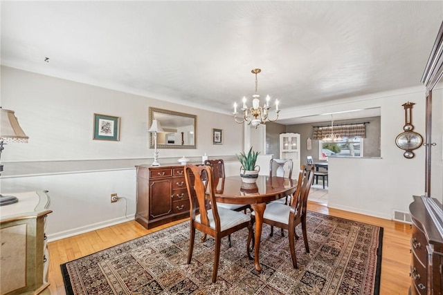 dining area with a notable chandelier and light hardwood / wood-style flooring