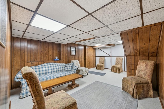 living area featuring a paneled ceiling and wooden walls