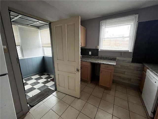 kitchen with a healthy amount of sunlight, white dishwasher, and wood walls