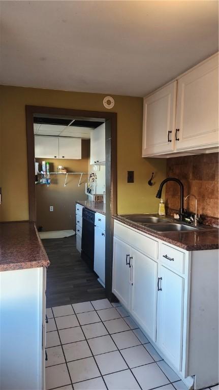 kitchen with white cabinetry, black dishwasher, and sink