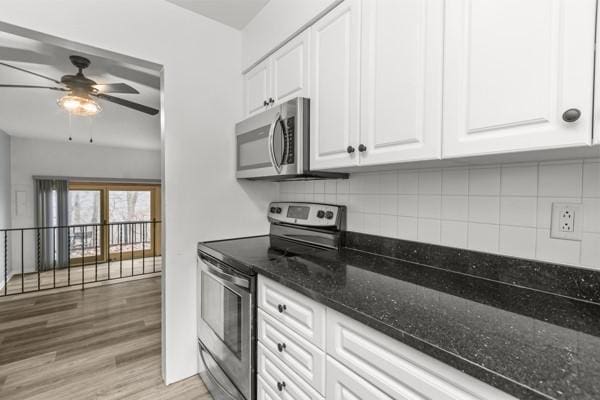 kitchen with tasteful backsplash, dark stone counters, stainless steel appliances, light hardwood / wood-style floors, and white cabinets