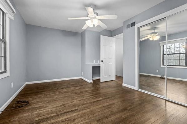 unfurnished bedroom with dark wood-type flooring, a closet, and ceiling fan