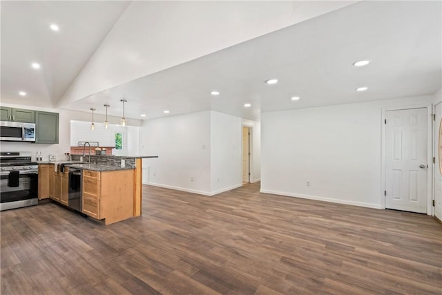 kitchen featuring dark wood-type flooring, hanging light fixtures, appliances with stainless steel finishes, kitchen peninsula, and stone counters